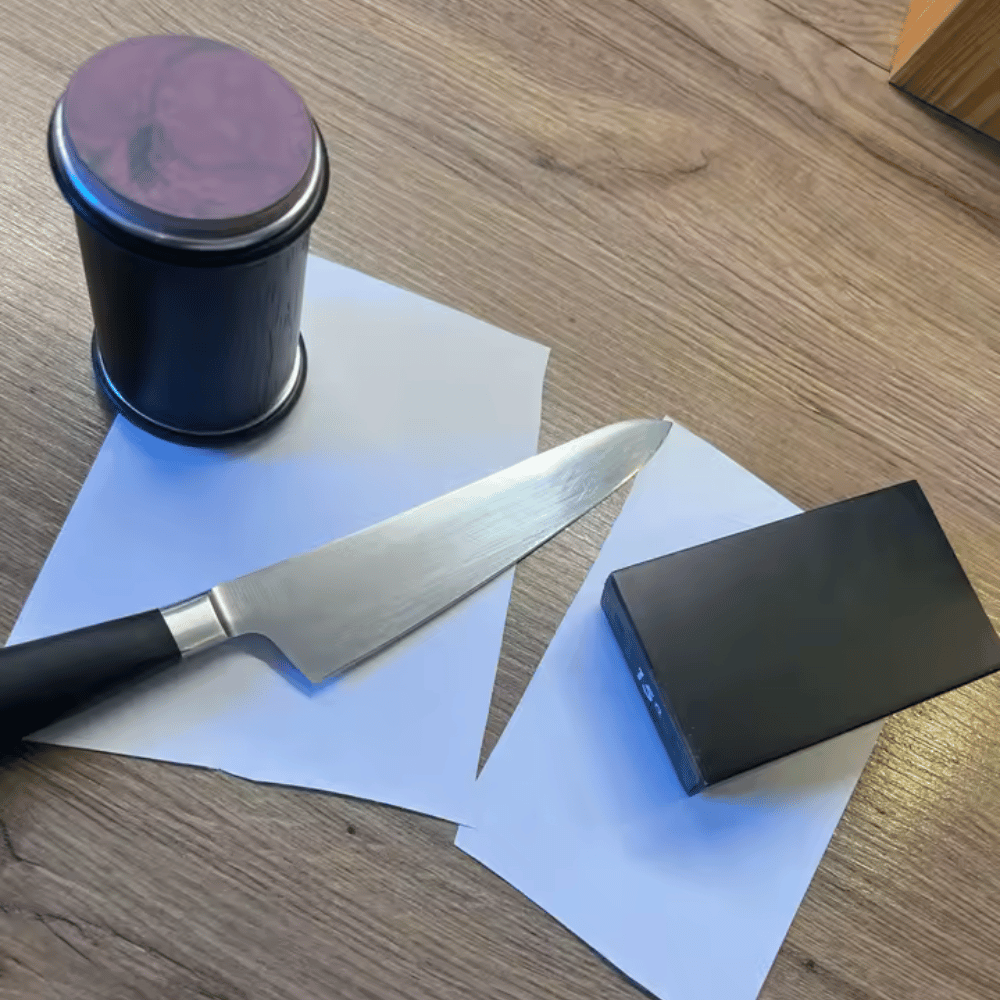 Knife, black sharpening stone, and container on a wooden surface