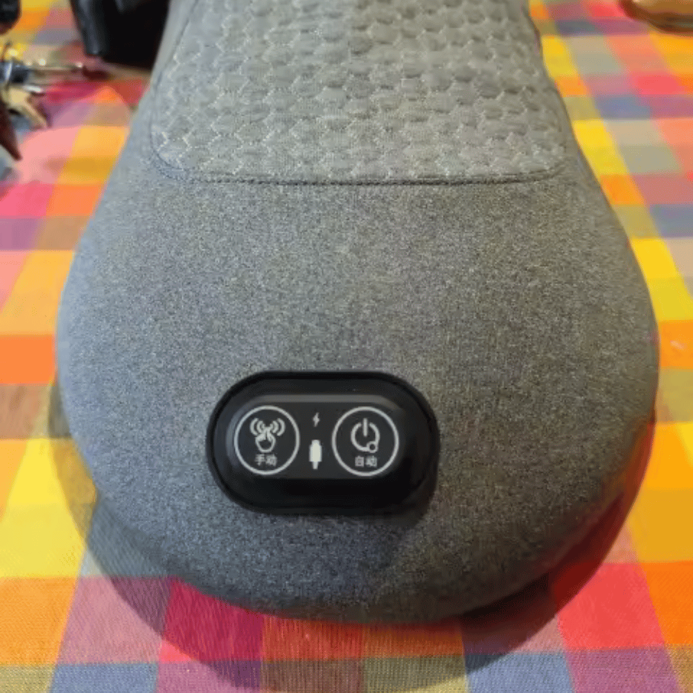 Gray massage pillow with control buttons on a colorful checkered tablecloth