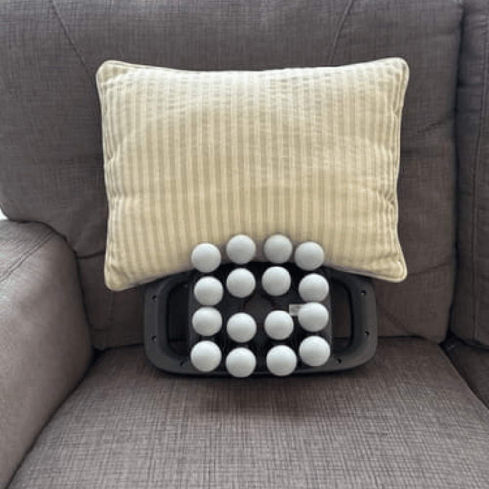 Massage pillow with white beads on a gray couch