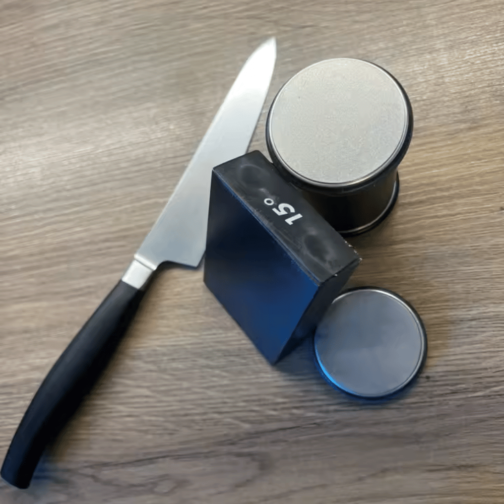 Knife, black sharpening stone, and container on a wooden surface
