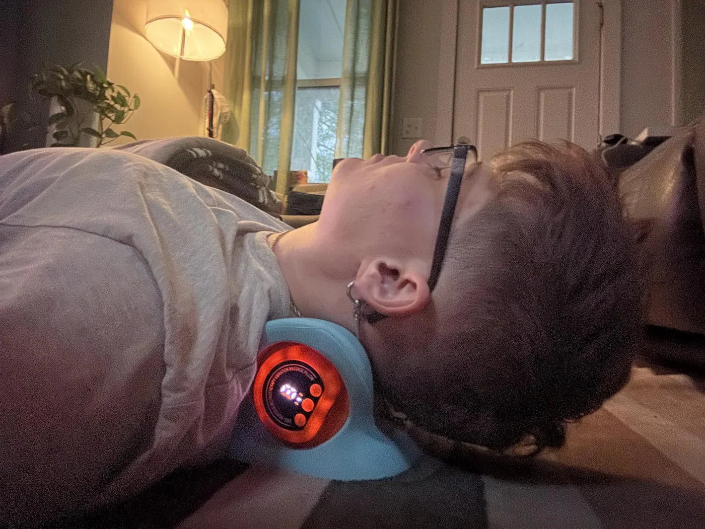 Person lying down with a neck massager on in a home setting