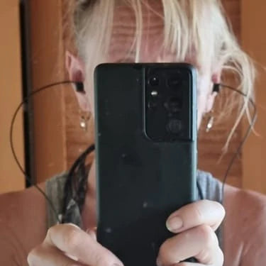 Person holding a black smartphone in front of a mirror