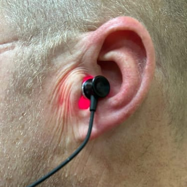 Ear with black earbud inserted, close-up view